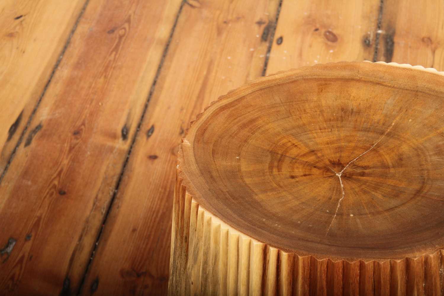 Close view of Alur Stool's carved teak grooves and rounded base