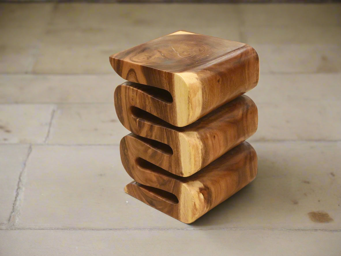 Front angle of the Arus Stool showing wave-like carved layers in natural wood.