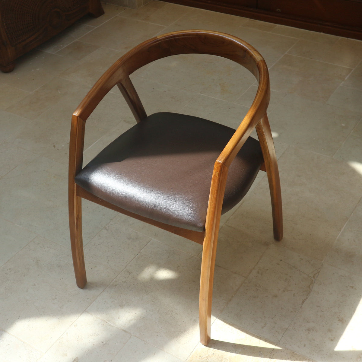 Lingkar Chair angled front view with curved teak backrest and dark seat